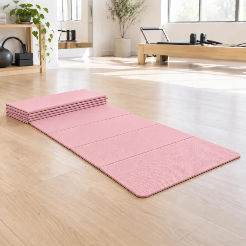 Faltbare Pilates Matte in Rosa, zur Hälfte gefaltet und zur Hälfte ausgeklappt auf Parkett, dahinter ein Reformer am Fenster